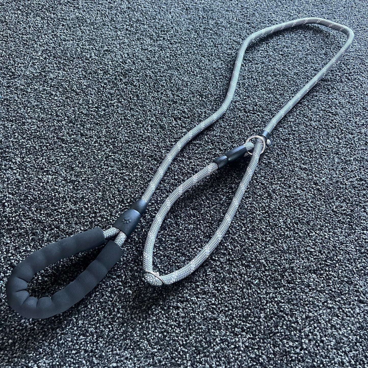 Gray dog leash with black handle on a textured gray surface