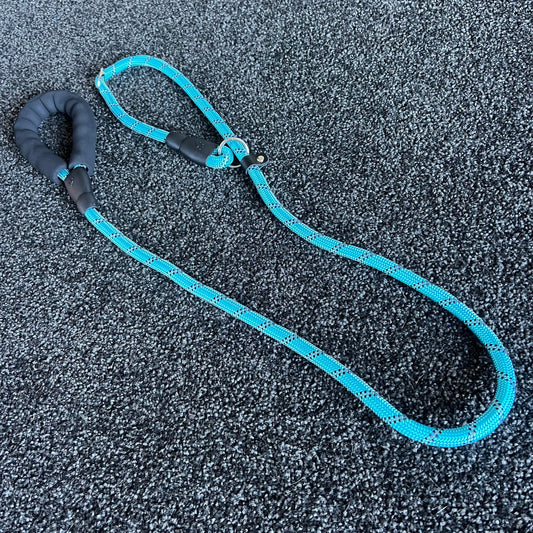 Blue dog leash with black handle on a textured gray surface