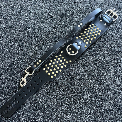 Black leather strap with gold studs and a smiley face design on a textured black background