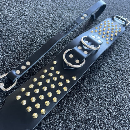 Black leather strap with gold studs on a textured black surface