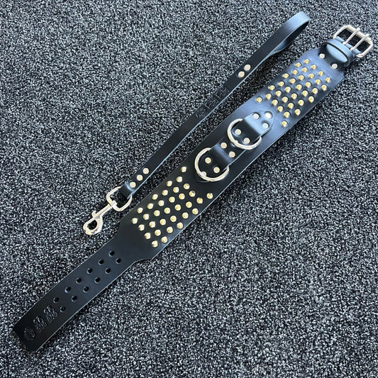 Black leather strap with gold studs on a textured gray background