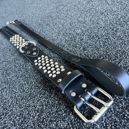Black leather belt with silver studs and buckle on a textured gray surface