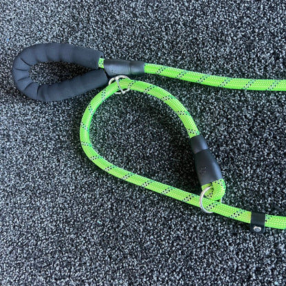 Green dog leash with black handle on a textured gray surface