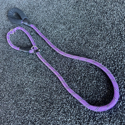 Purple dog leash with black handle on a textured gray surface