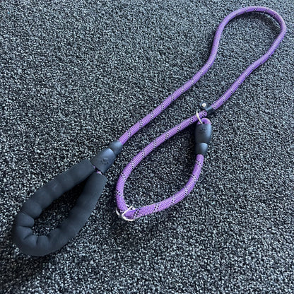 Purple dog leash with black handle on a textured gray surface
