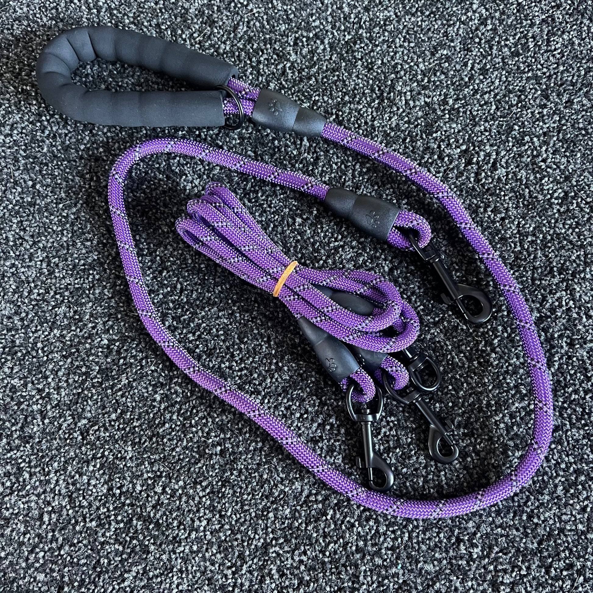 Purple dog leash with black handle on a textured gray surface