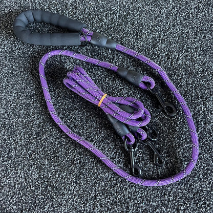 Purple dog leash with black handle on a textured gray surface