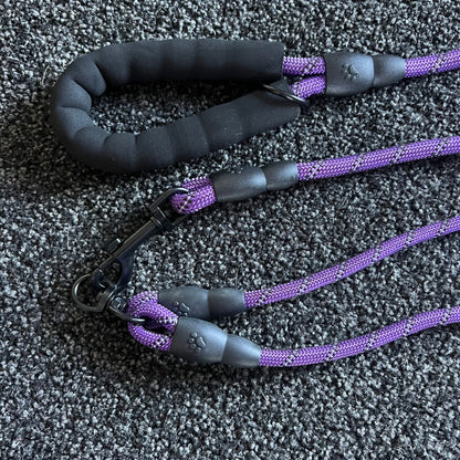 Purple and black dog leash on a textured gray surface